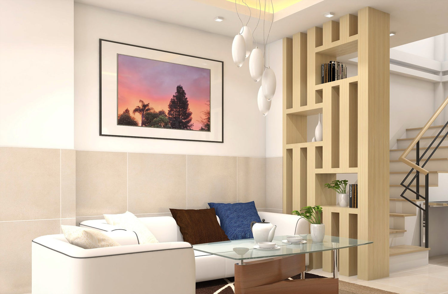 Framed wall art print titled “Cloud Photography” featuring a dramatic sunset sky with vivid pink, orange, and purple hues behind silhouettes of tropical trees. Displayed above a modern white sofa in a contemporary living room with minimalist decor.